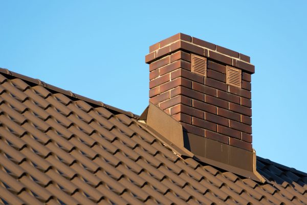 Brick chimney on the roof and clear blue sky